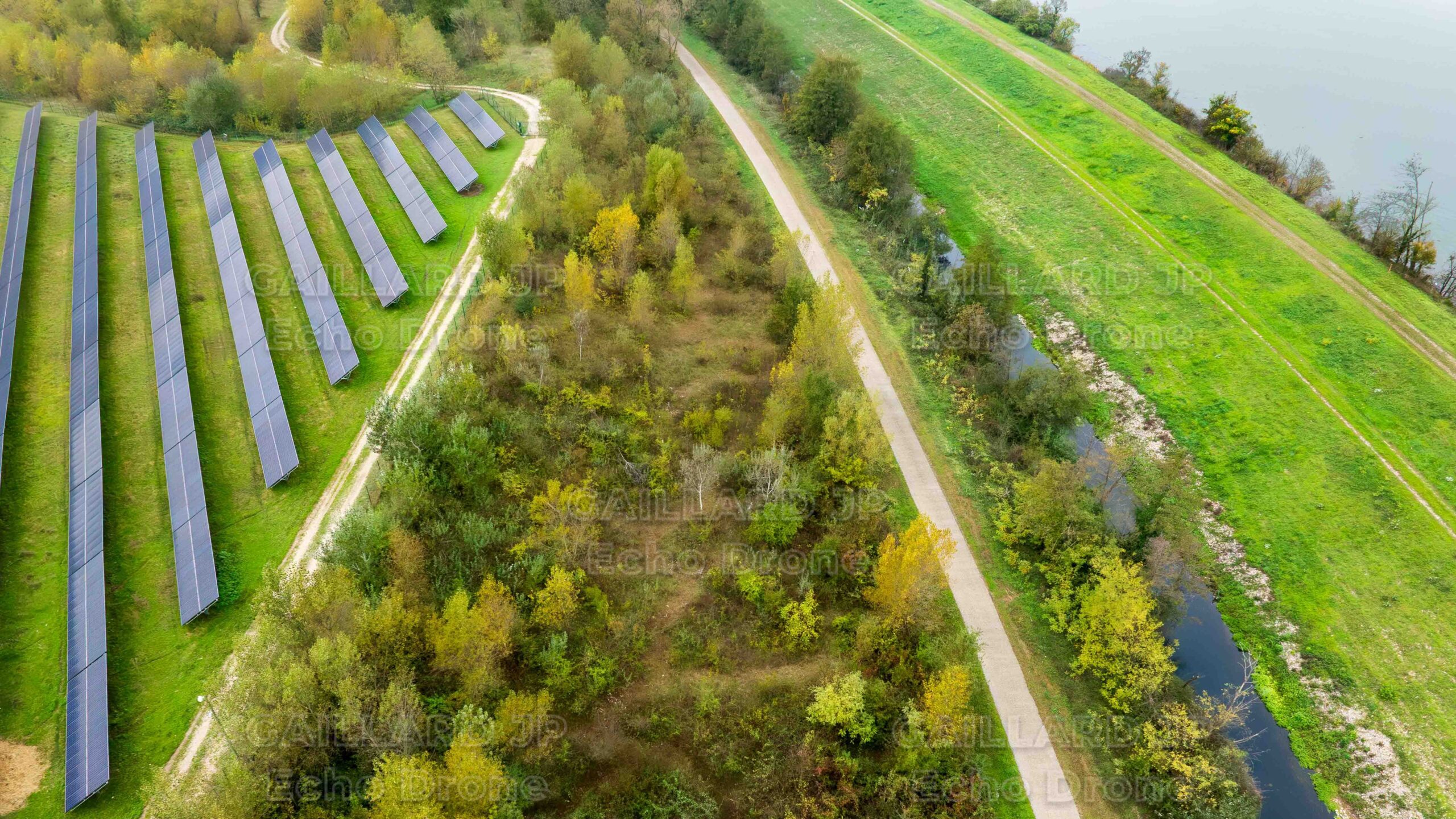 Vue aérienne d'une centrale solaire au sol jouxtant une zone forestière préservée, illustrant la limite de l'anthropisation et la nécessité d'une éthique du drone pour protéger les refuges de la faune.